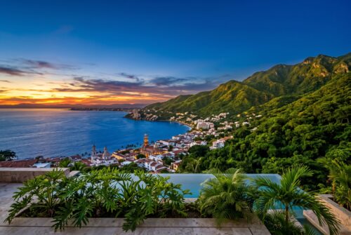 Panoramic sunset view of the blue ocean and green Sierra Madre mountains, showcasing the top things to do in Puerto Vallarta.